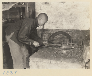 Coppersmith heating a piece of metal in a workshop