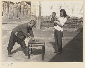 Woman and child watching a furniture maker working on a table, Furniture Street, Peking