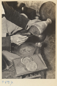 Coppersmith applying solder to a piece of metal in a workshop