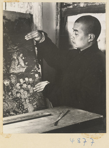 Man in a scroll-mounting shop removing a rebacked scroll painting from a drying board called a zhuang ban