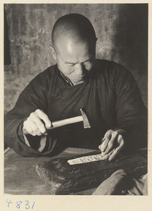 Silversmith hammering designs into a piece of silver in a workshop