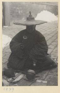 Man in wide-brimmed hat playing handchime and mu yu at New Year's