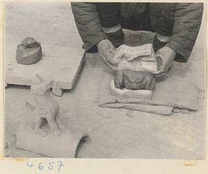 Man molding a ceramic roof ornament in the form of an animal figure at a tile and brick factory near Mentougou Qu