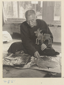 Puppeteer seated with shadow puppets