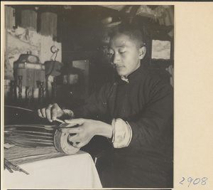 Man attaching ribs to lantern base in a lantern-making shop