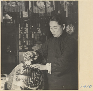 Man pasting characters onto a lantern in a lantern-making shop