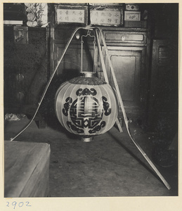 Lantern inscribed with the character xi hanging from a tripod stand in a lantern-making shop