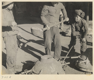 Men about to pour molten iron into a mold at a foundry near Mentougou Qu