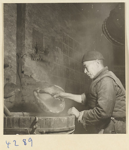 Man with a pumpkin-shell ladle working over a vat in a tofu-making shop