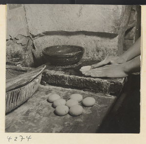 Kitchen interior showing a man shaping dough to make ma bing