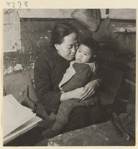 Woman holding a child in a metal-working shop