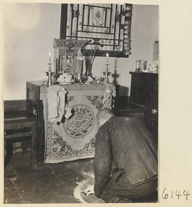 Man kneeling before a household altar at New Year's