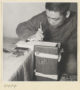 Man writing title and volume numbers on the heels of the fascicles of a multi-volume book