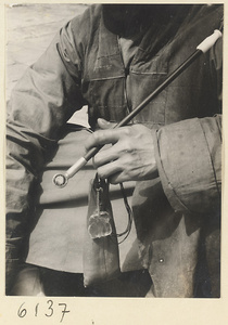 Man holding a pipe and a tobacco pouch with a glass toggle