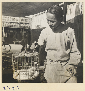 Woman using wooden tweezers to place food in a bird cage at a bird market