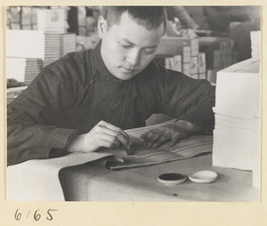 Monk at work in the bindery of a Buddhist temple