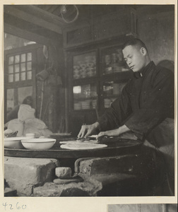 Restaurant interior showing a chef brushing water over dough to make shao bing