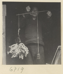 Man weighing a bundle of silk skeins