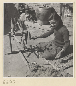Woman spinning cotton outdoors