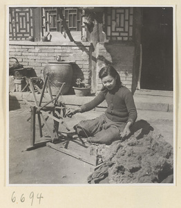 Woman spinning cotton outdoors
