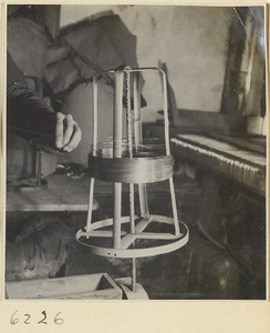 Interior of copper-net factory showing a man winding copper wire from a spool onto a shuttle