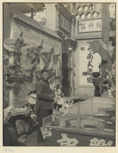 Boy selling kites next to building with inscriptions
