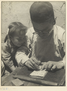 Girl watching man making paper-cuts