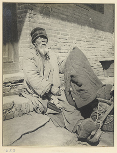 Seated man hawking second-hand clothes