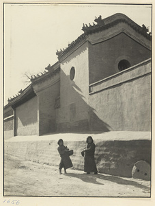 Two children in street next to building with roof ornaments