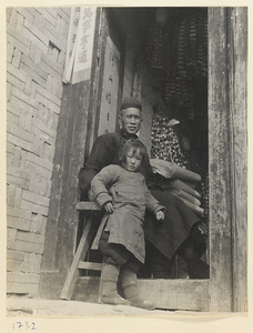 Man and girl in a doorway with auspicious couplets