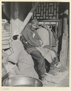 Man sitting on sacks outside a shop