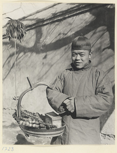 Street vendor hawking cigarettes and candied fruit called tang hu lu from a basket