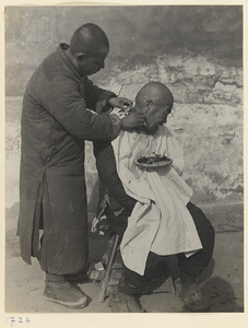 Street barber shaving a customer's head