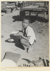 Boy eating at market next to a cart and a display of items for sale