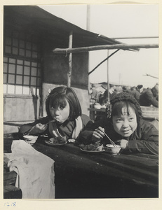Two girls eating at a food stand