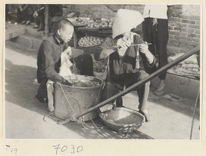 Street vendor weighing goods next to a produce stand in Qufu