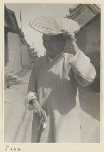 Woman with fan and cane on a street in Tai'an