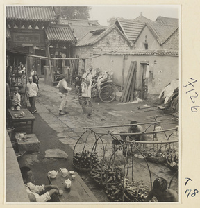 Village street in Ji'nan showing gate, rickshaw stand, and produce market
