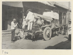 Men tying goods to a cart on a street in Tai'an