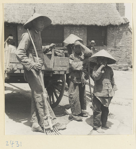 Man and boys with rakes standing next to a cart in a fishing village on the Shandong coast