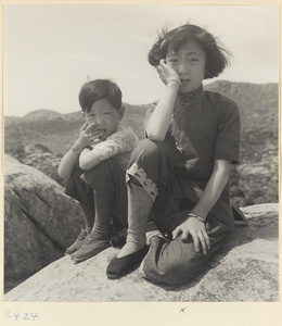 Boy and girl sitting on a rock in a fishing village on the Shandong coast