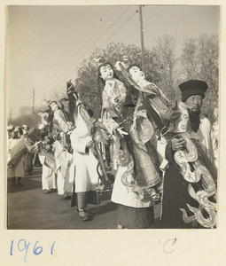 Members of a funeral procession carrying paper figures of female servants