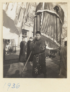 Member of a funeral procession carrying an umbrella with inscriptions