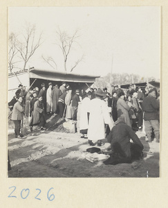 Members of a funeral procession outside a mat shed