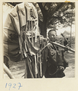 Boy with an umbrella for a funeral procession resting on his shoulder