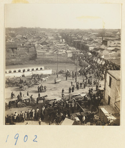 Funeral procession with draped coffin and automobiles crossing bridge over city moat