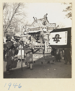 Members of a funeral procession carrying a paper replica of a pavilion and a eulogistic inscription