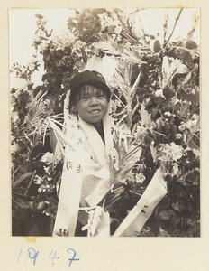 Member of a funeral procession carrying flower wreaths with inscriptions
