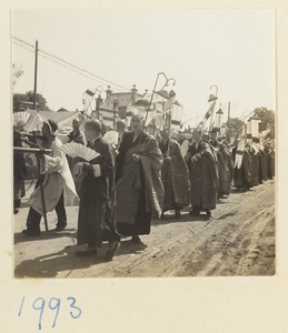 Buddhist monks carrying fans and Buddha banners in a funeral procession