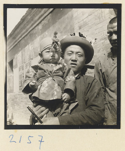 Father and child wearing hats decorated with souvenirs on the pilgrimage trail up Miaofeng Mountain